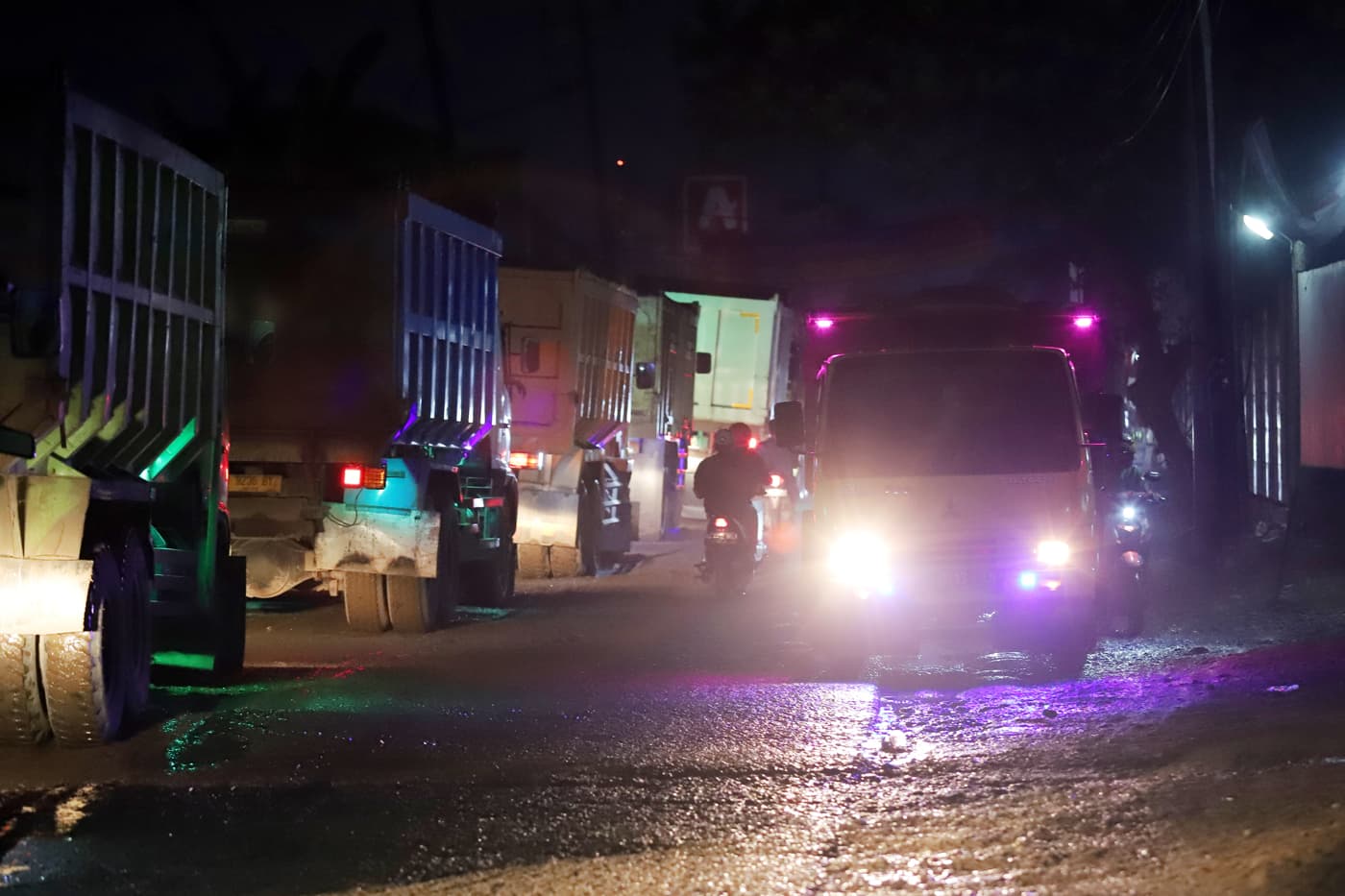 Sejumlah pengendara sepeda motor melewati jalan yang di lewati truk-truk tambang di Parung Panjang, Bogor, Jawa Barat, Kamis (23/11/2023). Kondisi Jalan Parung Panjang terlihat sangat parah. Terdapat banyak lubang hingga aspal yang tidak rata di sepanjan - Image