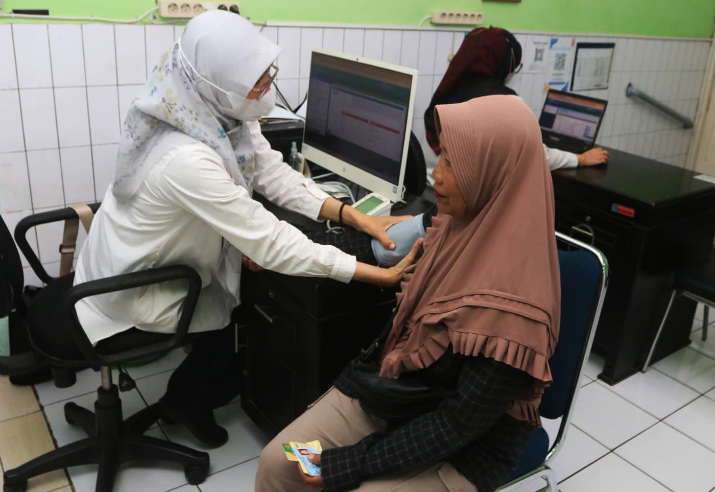 Petugas melayani warga saat pengurusan kepesertaan Jaminan Kesehatan Nasional (JKN) saat pelayanan BPJS Kesehatan Keliling dengan mobile customer service di Puskesmas Lebdosari,Kota Semarang, Jawa Tengah, Rabu (21/1/2026). (Nur Chamim/Jawa Pos Radar Semar - Image