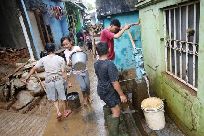 Warga mengantri mengambil air dari pompa manual pascabanjir yang melanda kawasan Cililitan Kecil, Jakarta, Jumat (3/1/2020). Warga mengambil air dari pompa manual dikarenakan listrik dan PAM belum menyala. Air tersebut digunakan untuk membersih rumah dan - Image