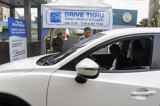 Petugas Amil Zakat menerima pembayaran Zakat melalui sistem Drive Thru dari kendaraan dari warga yang menyalurkan zakat di halaman Masjid Nurul Hidayah, Tanah Kusir, Jakarta, Jumat, (22/5/2020). Layanan penerimaan (pembayaran) zakat dengan sistem Drive T - Image