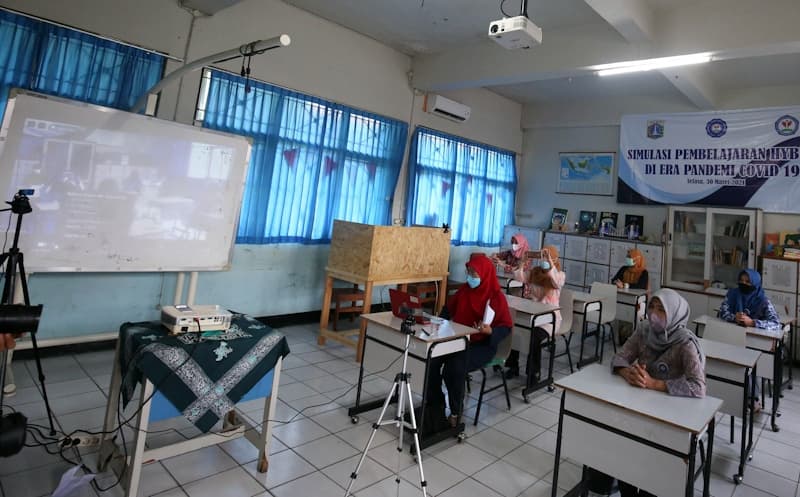Guru beserta orang tua murid mengikuti simulasi sekolah campuran tatap muka dan daring (hybrid) di SMP 255, Jakarta Timur, Selasa (30/3/2021). Kegiatan ini dilakukan untuk mengenalkan orang tua murid mengenai tata cara sekolah tatap muka yang rencana akan - Image