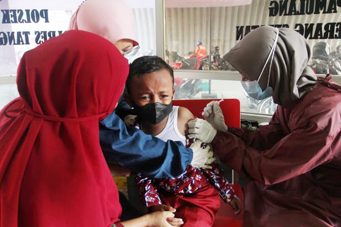 Tenaga kesehatan menyuntikan vaksin COVID-19 ke Ke anak-anak usai 6-11 tahun di kawasan kolong Jalan Layang Gaplek, Pamulang, Tangerang Selatan, Banten, Kamis (6/1/2022). Polsek Pamulang dibantu Dokkes Polda Metro Jaya memberikan Vaksinasi COVID-19 kepada - Image