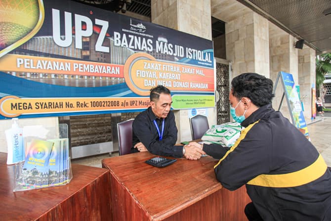 Warga membayar zakat di stan pelayanan zakat fitrah, Masjid Istiqlal, Jakarta Kamis, (28/4/2022). Baznas Masjid Istiqlal membuka layanan zakat fitrah hingga malam takbiran dengan besaran 3,5 liter atau 2,7 kilogram beras atau uang sebesar Rp50.000 per ora - Image