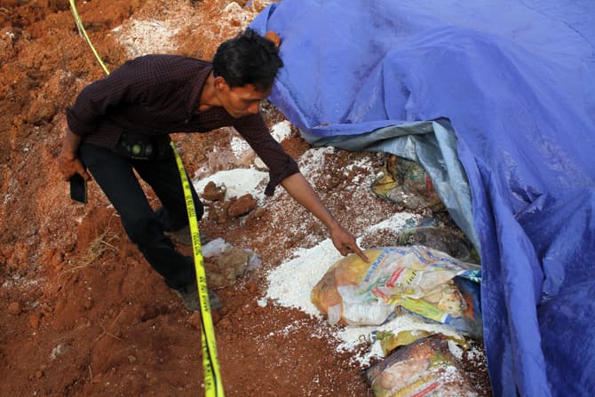 Garis polisi terpasang di area temuan karungan beras di tanah lapang Kampung Serab, Sukmajaya, Depok, Minggu (31/7/2022). Perusahaan pengiriman barang atau jasa ekspedisi diduga mengubur dan membuang puluhan karung beras untuk masyarakat terkena dampak CO - Image
